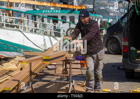 Shipwright Tischler Schneiden eine Planke aus Teakholz mit einem Hitachi elektrischen Kreissäge Stockfoto