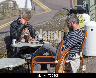 2 Männer sassen draussen eine Bar, ein Pub in der Sonne Trinkgläser von Irish Stout Bier Stockfoto