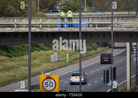 London, Großbritannien. 19. April 2019. Polizisten wachen von einer Fußgängerbrücke über die Autobahn Ansatz zum Flughafen Heathrow nach einem kleinen Protest früher vom Aussterben der Rebellion der Jugend. Ein grosses Polizeiaufgebot ist offensichtlich um den Flughafen aber bisher jede Unterbrechung von den Flughafenbehörden vom Aussterben Rebellion Klimawandel Aktivisten befürchtet hat, eher symbolische als Material. Credit: Mark Kerrison/Alamy leben Nachrichten Stockfoto