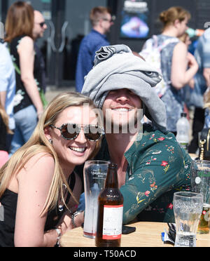 Brighton, UK. 19 Apr, 2019. Dieses chap versucht die sonne aus seinem Kopf zu halten, wie die Besucher in Scharen zu Brighton Beach die Sonne zu genießen, da die Temperaturen Mitte der 20er Jahre entlang der Südküste: Simon Dack/Alamy Leben Nachrichten erreichen Stockfoto