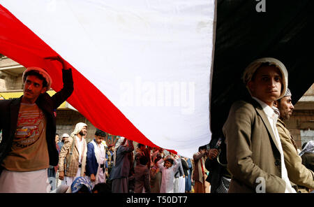 Sanaa, Jemen. 19 Apr, 2019. Jemeniten halten ein Jemen Nationalflagge auf einer Kundgebung in Sanaa, Jemen, am 19. April 2019. Tausende von Jemeniten nahmen an einer Kundgebung hier am Freitag gegen die Fortsetzung des Krieges und der Blockade zu Jemen auferlegt. Jemenitische politischen Analysten sagen, dass US-Präsident Donald Trump Veto gegen eine Resolution des Kongresses, die versuchte, die ein Ende der US-Beteiligung im Jemen Die wichtigsten amerikanischen Rolle im Krieg beweist. Credit: Mohammed Mohammed/Xinhua/Alamy leben Nachrichten Stockfoto