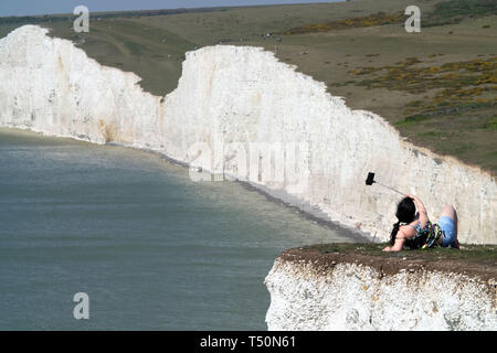 Birling Gap, East Sussex, UK. 20. April 2019. Die ungewöhnlich warmen Wetter hat gesehen, tausende von Touristen strömen zu den ikonischen Sieben Schwestern Kreidefelsen in der Nähe von Eastbourne, East Sussex, von denen viele gefährliche selfieis auf der unstable Klippe. Ein Mann wurde gesehen baumelt ein kleines Kind in seine Arme, als er über die schiere Drop spähte. Die Klippen sind bis zu 400 Fuß hoch und sind eine bekannte Selbstmord. © Peter Cripps/Alamy leben Nachrichten Stockfoto