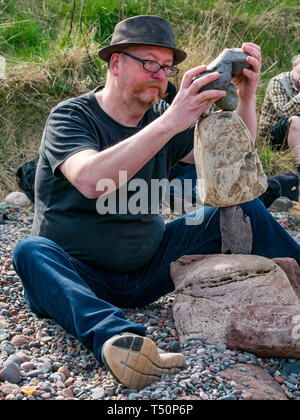 Dunbar, East Lothian, Schottland, Vereinigtes Königreich. 20 Apr, 2019. Europäische Stein stacking Meisterschaft: Neil Andrews Salden Steine in den 5 Steinen in 3 Minuten Wettbewerb auf Augenhöhe Cave Beach gestapelt Stockfoto