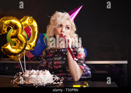 Glückliche junge Frau, die Spaß an der Geburtstagsparty. Charmant und attraktiv und festliche Kuchen. Die Kerzen in der Kuchen Stockfoto