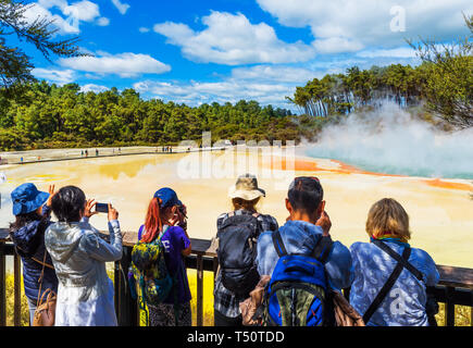 ROTORUA, NEUSEELAND - 10. OKTOBER 2018: eine Gruppe von Menschen auf dem Hintergrund der geothermischen Pools in Wai-O-Tapu Park Stockfoto