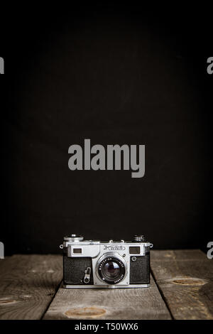 Alte vintage Foto kamera mit schwarzem Hintergrund auf einem Holztisch Stockfoto
