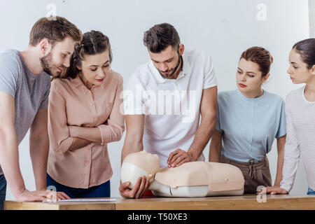 Gruppe von Zusammengeschlossenen Menschen mit Hlw-dummy während Erste Hilfe training Stockfoto