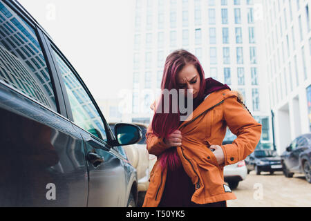 Hübsche junge Frau stehen und die Schlüssel des Autos in ihrer Tasche im Freien. Stockfoto