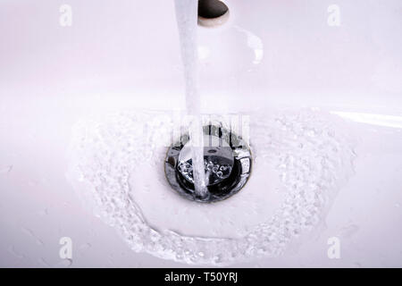 Fließendes Wasser in der Spüle mit Stecker und Wasser Stockfoto