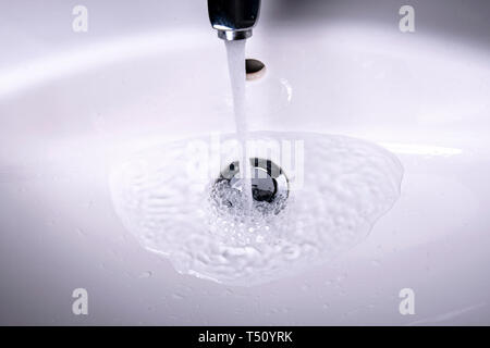 Fließendes Wasser in der Spüle mit Stecker und Wasser Stockfoto