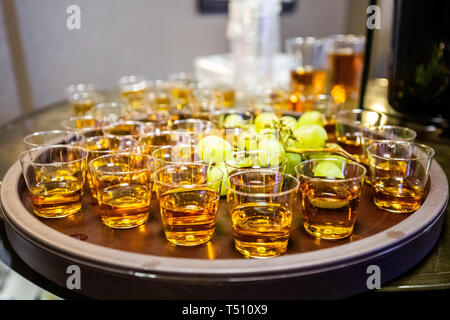 Alkoholische Schüsse auf einem Tablett in verschwommenen Bar mit Trauben Stockfoto