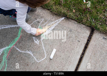 Ein kleines Mädchen, zieht mit sidewalk Chalk an einem sonnigen Frühlingstag. Stockfoto