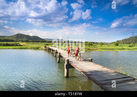 Phu Yen Provinz, Vietnam - Juli 9, 2017: In einer kleinen, ruhigen Dorf in Phu Yen Provinz, Vietnam, spielen Kinder Drachen, Radfahren auf einer Brücke gemacht Stockfoto