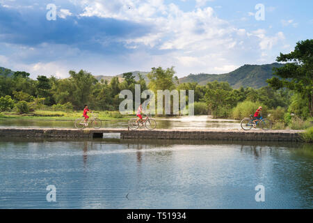 Phu Yen Provinz, Vietnam - Juli 9, 2017: In einer kleinen, ruhigen Dorf in Phu Yen Provinz, Vietnam, spielen Kinder Drachen, Radfahren auf einer Brücke gemacht Stockfoto