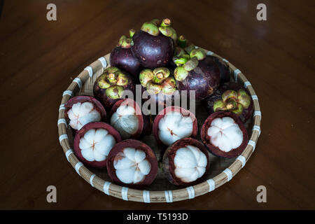 Mangostanfrüchte in Bambus Korb auf schwarzem Hintergrund Stockfoto