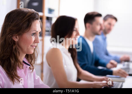 Lächelnden jungen Geschäft Leute sitzen in einem EDV-Zeile Stockfoto