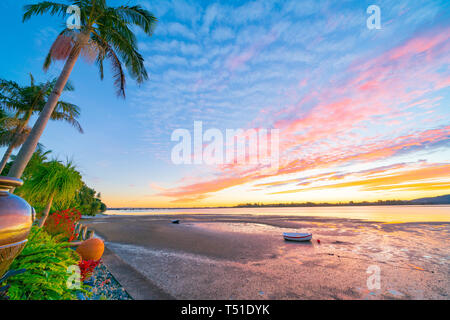 Brillante Sonnenuntergang am Hafen Kante mit markanten Wolkenformationen über den tropischen Garten und Strand bei Ebbe Tauranga Neuseeland Stockfoto