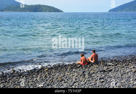 Touristen sitzen auf der schönen Rocky Beach, Koh hin Ngam, Tarutao Marine National Park in Songkhla Provinz, Thailand Stockfoto