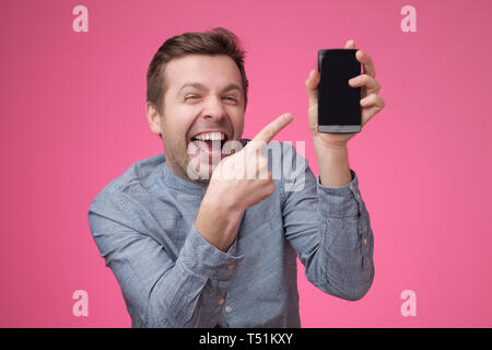 Lustig junge europäische Mann, der auf dem Telefondisplay auf seinem Smartphone Stockfoto