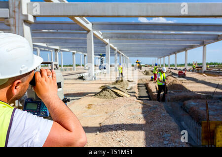 Vermesser Ingenieur misst Ebene auf Baustelle. Vermessungsingenieure sorgen für präzise Messungen vor dem Unternehmen große Bauvorhaben. Stockfoto