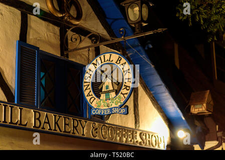 Runde Zeichen vor Fenster hängen an der Stange Bügeleisen mit Lampe oben. Bäckerei unterzeichnen. Stockfoto