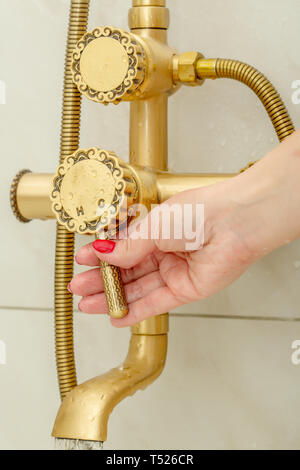 Famale hand schaltet eine Dusche Wasserhahn im Vintage Style kaltes und heißes Wasser im Badezimmer Stockfoto