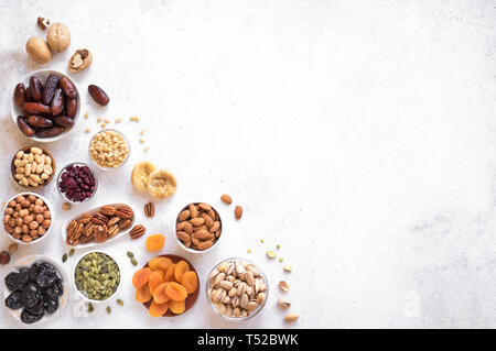 Trockenfrüchte und Nüsse in Schalen auf weißem Hintergrund, Ansicht von oben, kopieren. Gesunde snack-Sortiment von Bio Trockenfrüchte und Nüsse. Stockfoto