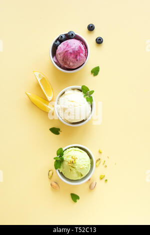 Eis Sortiment. Verschiedene Früchte und Beeren Eis auf gelbem Hintergrund, kopieren. Gefrorener Joghurt oder Eis - gesunde Sommer Nachtisch. Stockfoto