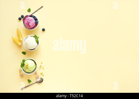 Eis Sortiment. Verschiedene Früchte und Beeren Eis auf gelbem Hintergrund, kopieren. Gefrorener Joghurt oder Eis - gesunde Sommer Nachtisch. Stockfoto