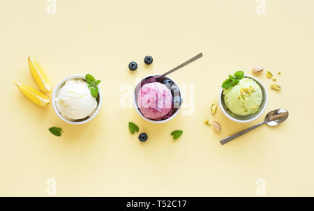 Eis Sortiment. Verschiedene Früchte und Beeren Eis auf gelbem Hintergrund, kopieren. Gefrorener Joghurt oder Eis - gesunde Sommer Nachtisch. Stockfoto