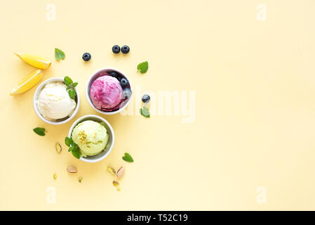 Eis Sortiment. Verschiedene Früchte und Beeren Eis auf gelbem Hintergrund, kopieren. Gefrorener Joghurt oder Eis - gesunde Sommer Nachtisch. Stockfoto