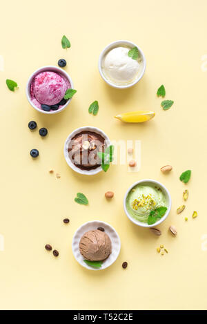 Eis Sortiment. Verschiedene Früchte und Beeren Eis auf gelbem Hintergrund, kopieren. Gefrorener Joghurt oder Eis - gesunde Sommer Nachtisch. Stockfoto