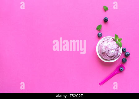 Heidelbeere Eis auf rosa Hintergrund, Ansicht von oben, kopieren. Kugel Gelato in Schale mit Blaubeeren und Minze. Stockfoto