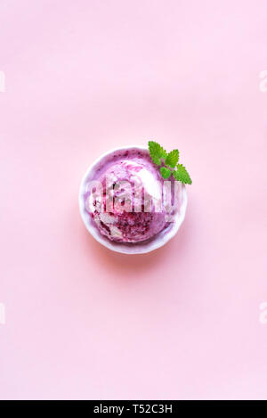 Rosa Eis auf rosa Hintergrund, Ansicht von oben, kopieren. Scoop der Heidelbeeren oder Beeren Gelato in Schale mit Plastiklöffel. Stockfoto