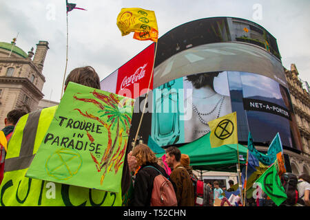 Umweltaktivisten vor dem Aussterben Aufstandsbewegung wave Flags, zum Spielen mit Pauken und im Londoner Piccadilly Circus während Polizei zeigen auf Stockfoto