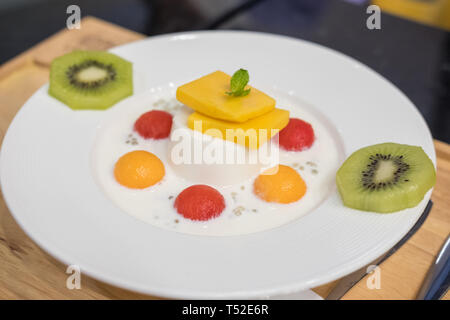 Panna Cotta mit Wassermelone, Melone, Mango, Kiwi auf dem Teller serviert. Stockfoto