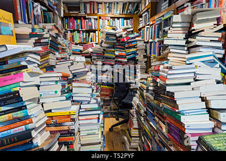 Unordnung und Stapel von Büchern füllen einen Raum für Platz über. Stockfoto