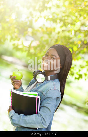 Porträt eines lächelnden afrikanische amerikanische Studentin, die einen grünen Apfel. Stockfoto