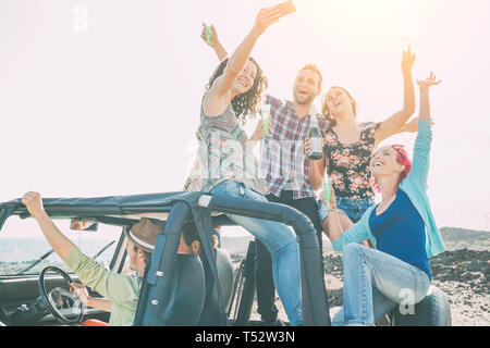 Gruppe von glücklich Making Friends Party auf einem Jeep Auto - Junge Leute Spaß trinken Champagner und unter Foto selfie während ihres Ausflugs Stockfoto