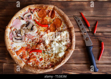 Composite pizza sortierten, getrocknete Chilischoten und Käse Messer liegen auf einem natürlichen Holz- Oberfläche der Kiefer Bretter. Tageslicht. Stockfoto