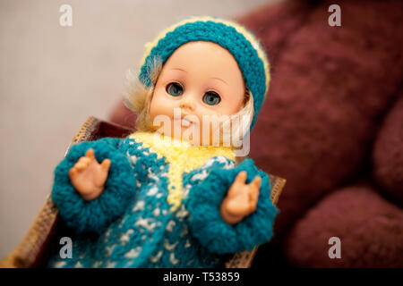 Altes Spielzeug ist ein Vintage Doll mit blauen Augen in einer Schirmmütze. Element aus der Vergangenheit. Geringe Tiefenschärfe. Stockfoto