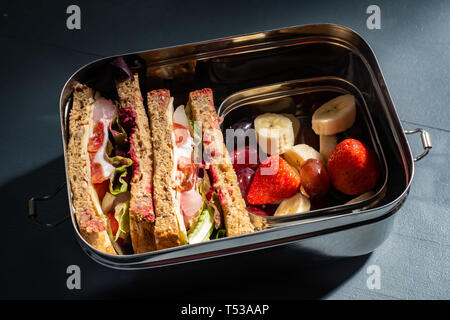 Gesunde Sandwiches auf Braun gesäte Brot und Obst Snacks in einem Edelstahl Lunch Box mit Fächern. Wiederverwendbare Edelstahl bedeutet keine p Stockfoto