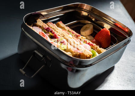 Gesunde Sandwiches auf Braun gesäte Brot und Obst Snacks in einem Edelstahl Lunch Box mit Fächern. Wiederverwendbare Edelstahl bedeutet keine p Stockfoto