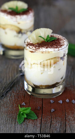 Konzept der italienischen Dessert. Ananas Tiramisu in einem Glas Tasse auf Holztisch. Nahaufnahme Stockfoto