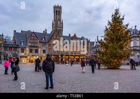 Menschen auf dem großen Marktplatz (Markt) im Zentrum von Brügge mit Weihnachtsbeleuchtung und mit großen Weihnachtsbaum dekoriert. Stockfoto