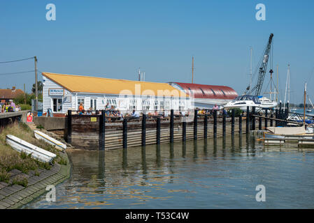 Die Teestube an Heybridge Basin, Essex, Großbritannien auf einem hellen, sonnigen Tag mit Menschen. River Blackwater mit Booten. Leute draußen genießen Wetter essen Stockfoto