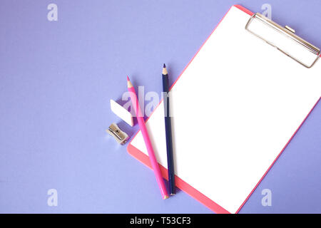 Bunte, fröhliche, bunte Bleistifte sind unten in einem Winkel und einem Notebook für Ihren Text auf einem violetten Hintergrund entfernt. Stockfoto