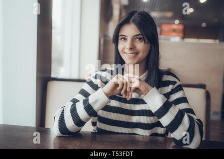 Schöne kaukasische Mädchen in Freizeitkleidung lächelnd, während im Cafe sitzen. Warme Stimmung