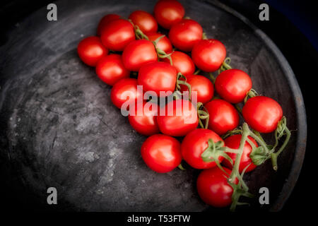 Ein Cluster von Red Cherry Tomaten auf einem schwarzen Fach Stockfoto