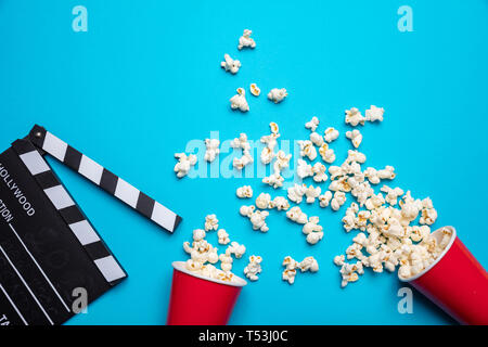 Kino für zwei Konzept. Frische salzige Pop Corn und Movie clapper Board, blaue Farbe Hintergrund, Ansicht von oben Stockfoto